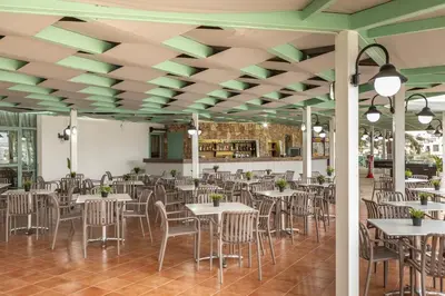 a dining room with tables and chairs and green ceilings at Antigoni Hotel in Protaras