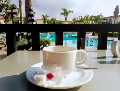 a coffee cup on a table with a view of a pool at Tsokkos Paradise Holiday Village in Ayia Napa