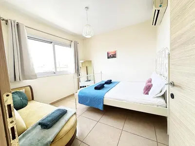 a bedroom with a bed and a chair in it at Angela's Sunset Holiday Apt - Ayia Napa in Ayia Napa