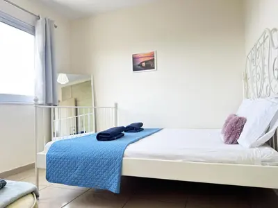 a bedroom with a bed with a blue blanket on it at Angela's Sunset Holiday Apt - Ayia Napa in Ayia Napa