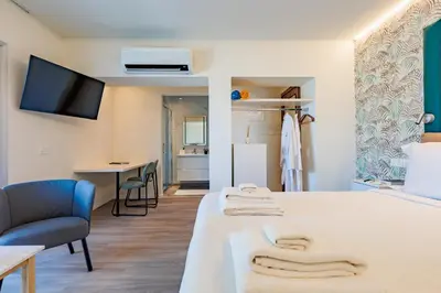 a room with a bed and a chair and a desk at The Palm Suites - Adults Only in Limassol