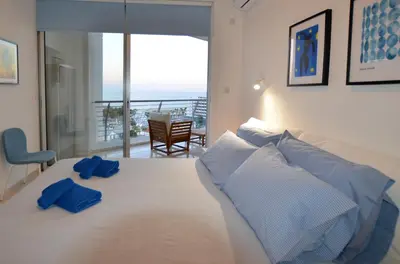 a bedroom with a white bed with blue pillows on it at Awesome Sea & Marina View City Center 1 Bdr Flat in Larnaka