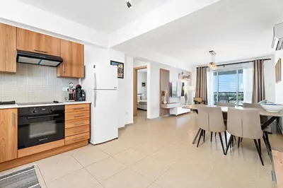 a kitchen with a white refrigerator and a table with chairs at Spitaki 2 BDR Apartment with Pool and Close Proximity to Beach in Paralimni