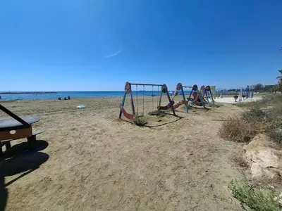 a group of people playing on a swing set on the beach at Seaside Escape Apartment in Larnaka