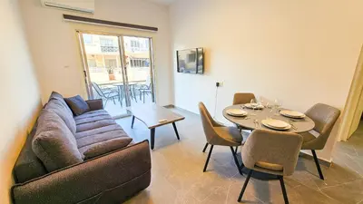 a living room with a couch and a table with chairs at La Magenta Apartments in Pyla
