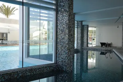 a house with a swimming pool and a tile wall at Vassos Nissi Plage Hotel & Spa in Ayia Napa