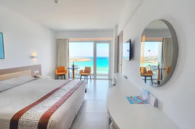 a hotel room with a bed and a mirror at Vassos Nissi Plage Hotel & Spa in Ayia Napa