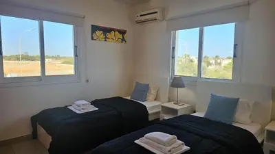 two beds in a room with two windows at STAY Villa Harsha in Ayia Napa