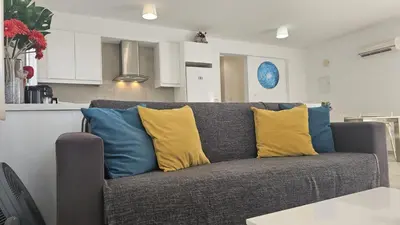 a gray couch with yellow and blue pillows in a kitchen at STAY Villa Harsha in Ayia Napa