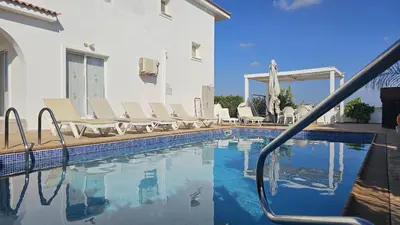a swimming pool with lounge chairs next to a building at STAY Villa Harsha in Ayia Napa