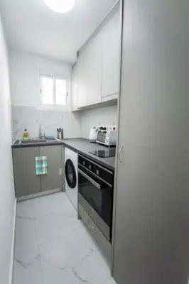 a kitchen with white cabinets and a black stove top oven at Limassol Centr Apartament in Limassol