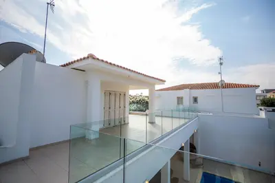 a glass balcony with a view of a house at Beachfront Villa Larnaka Dhekelia with Pool in Pyla