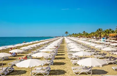a row of chairs and umbrellas on a beach at Mackenzie Suite in Larnaka