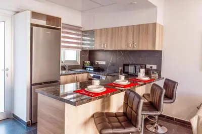 a kitchen with a counter with two chairs and a refrigerator at Mackenzie Suite in Larnaka