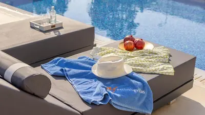 a table with a hat and fruit on it next to a pool at Nissi Residences Villa 4 in Ayia Napa
