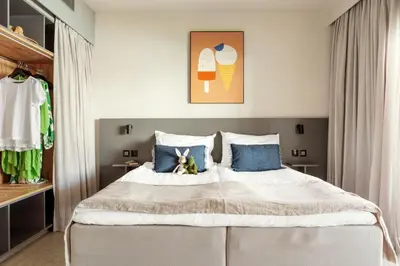 a bedroom with a large bed with blue pillows at SUNWING Sandy Bay Beach Village in Ayia Napa