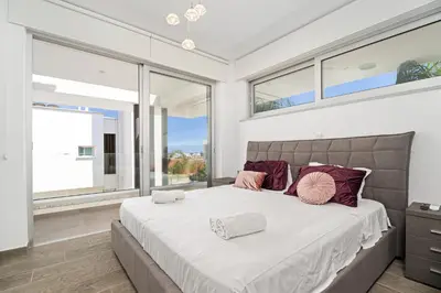 a bedroom with a large bed and large windows at Serene Villa Retreat in Protaras in Paralimni