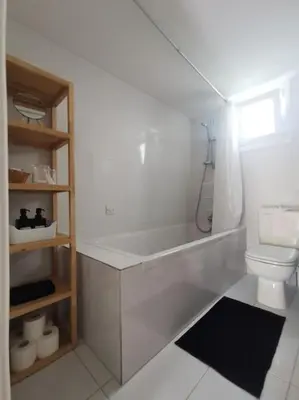 a white bathroom with a shower and a toilet at Cozy Family Home in Laxia