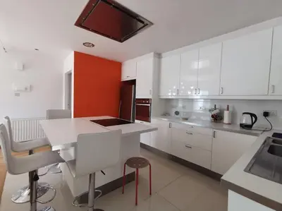 a kitchen with white cabinets and a table and chairs at Cozy Family Home in Laxia