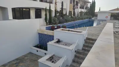 a white building with stairs next to a swimming pool at Emerald Heights in Tersephanou