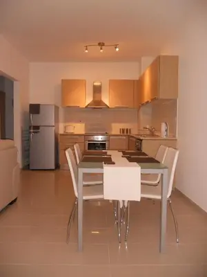 a kitchen with a dining table and white chairs at Emerald Heights in Tersephanou