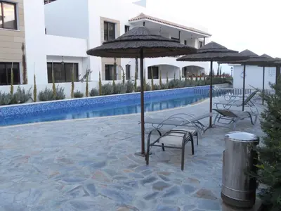 a group of chairs and umbrellas next to a pool at Emerald Heights in Tersephanou