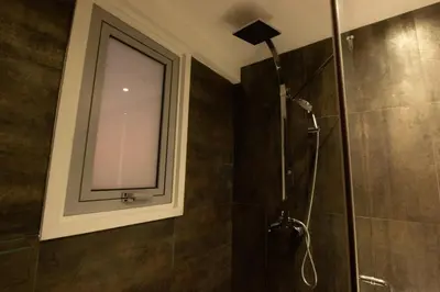a bathroom with a shower with a mirror and a window at Top Floor Gem: 3BR, Huge Veranda in Nicosia