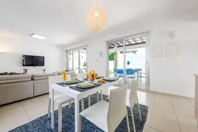 a white dining room with a white table and chairs at Konnos Breeze Villa in Protaras
