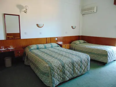 a hotel room with two beds and a mirror at Hellas Hotel in Kakopetria