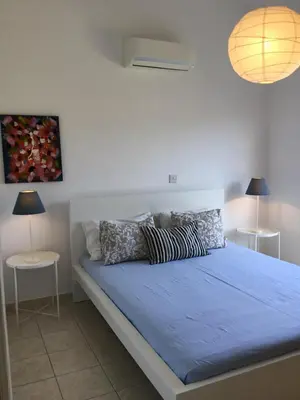 a bedroom with a bed with blue sheets and pillows at Pissouri Beach House - Image in Pissouri