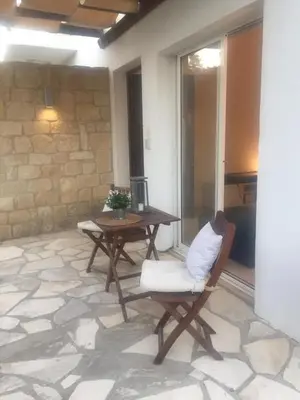 a patio with a table and a chair and a table at Pissouri Beach House - Image in Pissouri