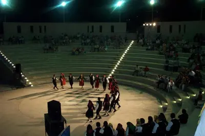 a group of people walking around a stage at night at Pissouri Beach House - Image in Pissouri