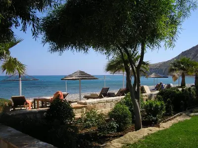 a beach with chairs and umbrellas and the ocean at Pissouri Beach House - Image in Pissouri
