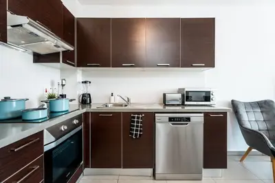 a kitchen with wooden cabinets and a dishwasher at SunnyVillas 1 Bedroom Swimming Pool COR in Protaras