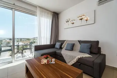 a living room with a couch and a table at SunnyVillas 1 Bedroom Swimming Pool COR in Protaras