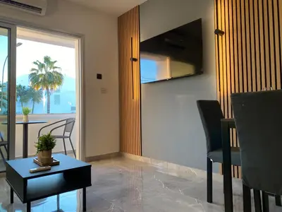 a living room with a table and chairs and a window at Nissi Avenue Studios in Ayia Napa