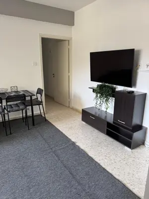 a living room with a flat screen tv and a table at Georges 2 Bedroom Apartment in Limassol