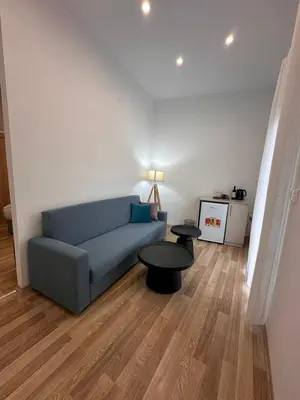 a living room with a blue couch and two tables at Joanna's Rooms in Kalopanayiotis