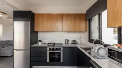 a kitchen with black and white cabinets and a refrigerator at Villa Iva by the Sea in Paralimni