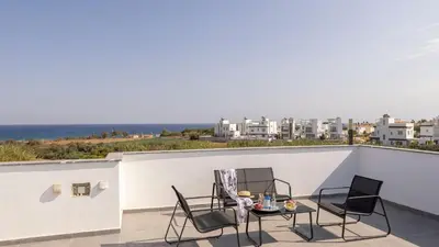 a balcony with two chairs and a table with a view of the ocean at Villa Iva by the Sea in Paralimni