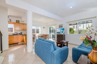 a living room with two blue chairs and a kitchen at Villa Kos #7 in Paralimni