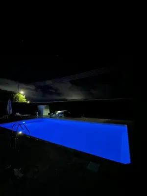 a blue swimming pool in the dark at night at Bohemian Oasis in Episkopi Lemesou