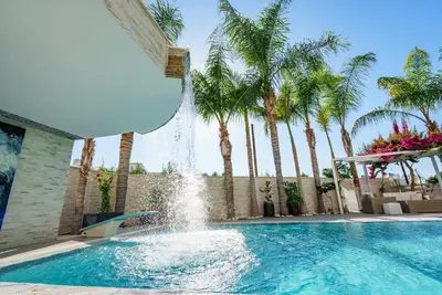 a fountain in a swimming pool with palm trees at Royal Nissi Mansion 3 bed lower part of villa in Ayia Napa