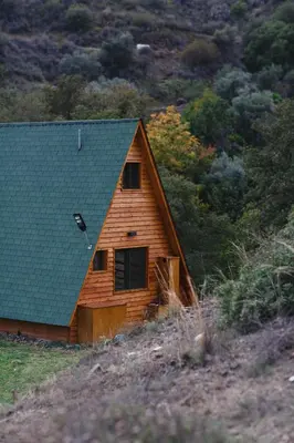 a wooden cabin with a green roof on a hill at Cozy Glamping Cabin for Couples and Families in Arakapas