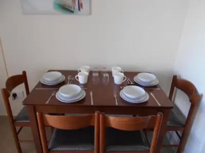 a wooden table with four chairs and plates and cups at Ayia Napa Apartment in Ayia Napa