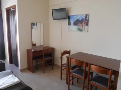 a room with a table and a desk and a television at Ayia Napa Apartment in Ayia Napa