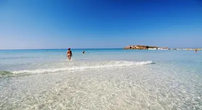 a person walking on a beach in the water at Ayia Napa Apartment in Ayia Napa