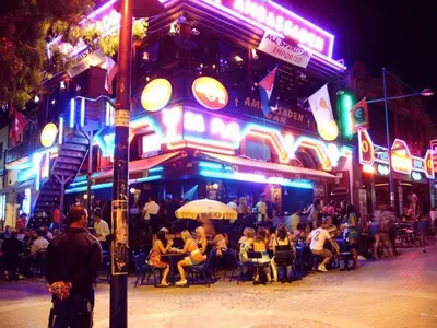 a group of people sitting outside a restaurant at night at Ayia Napa Apartment in Ayia Napa