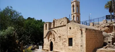a stone church with a clock tower on a hill at Ayia Napa Apartment in Ayia Napa