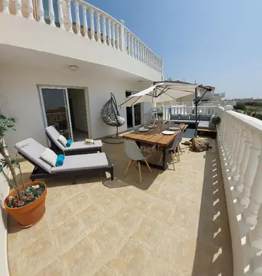 a patio with a table and chairs and an umbrella at Nissi Retreat - Walk to Nissi beach! in Ayia Napa